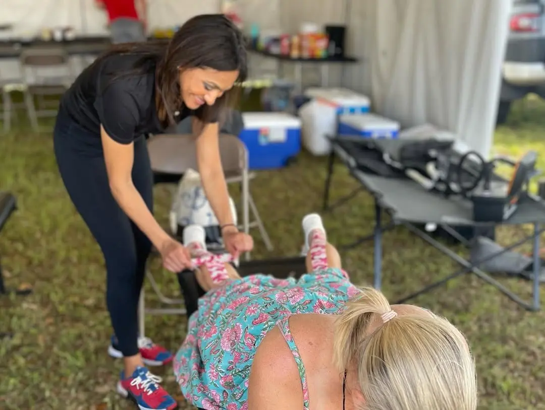 Dr Lisa Patel performing chiropractic on a female leg at athlete event in Katy Texas
